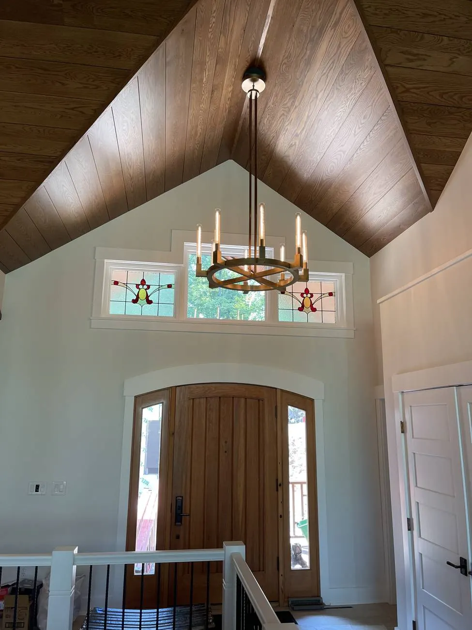 Two-story entry with wood ceiling, stained glass transom and a large chandelier