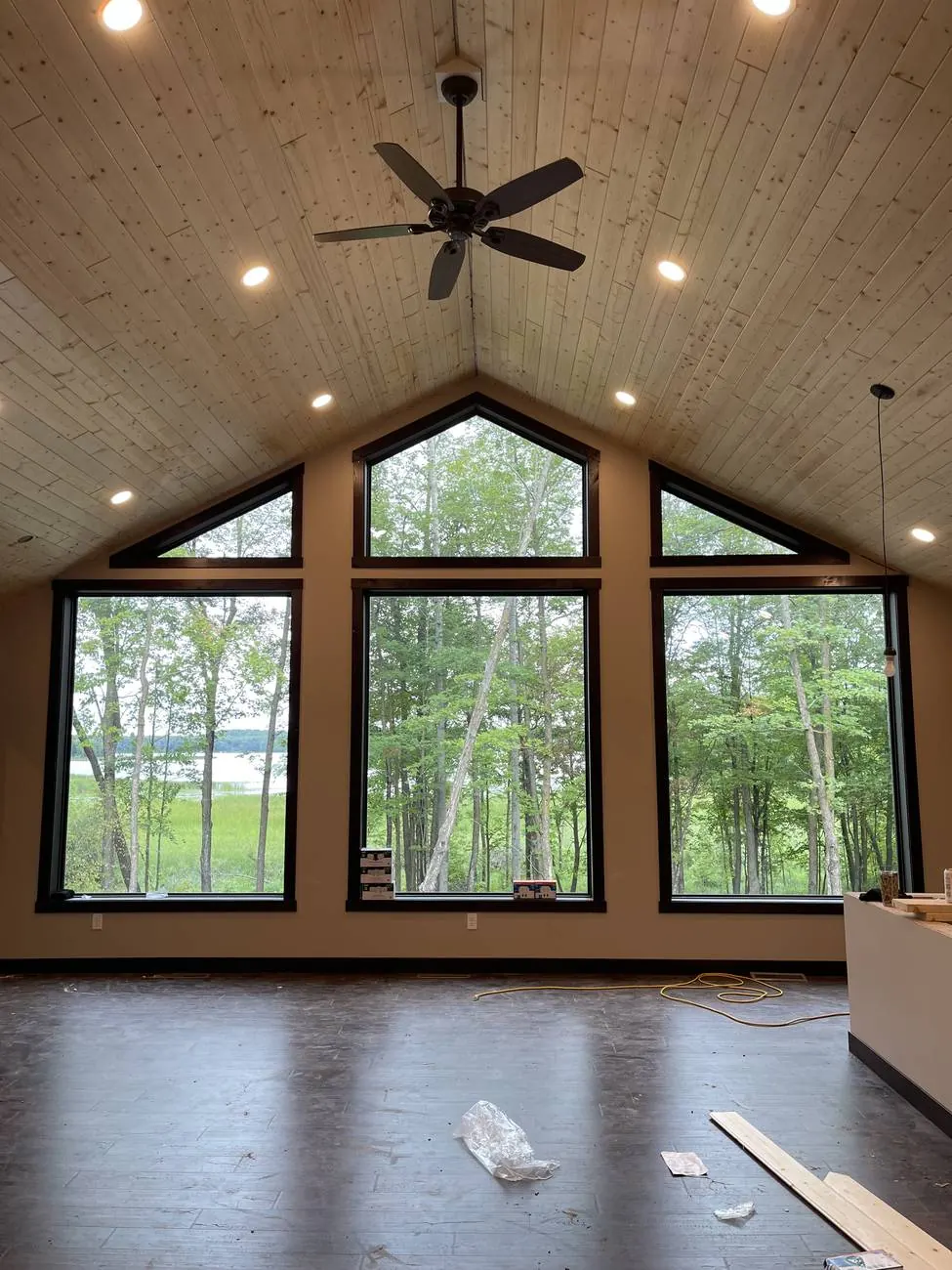 Vaulted great room with pine ceiling, ceiling fan and recessed lighting overlooking a lake
