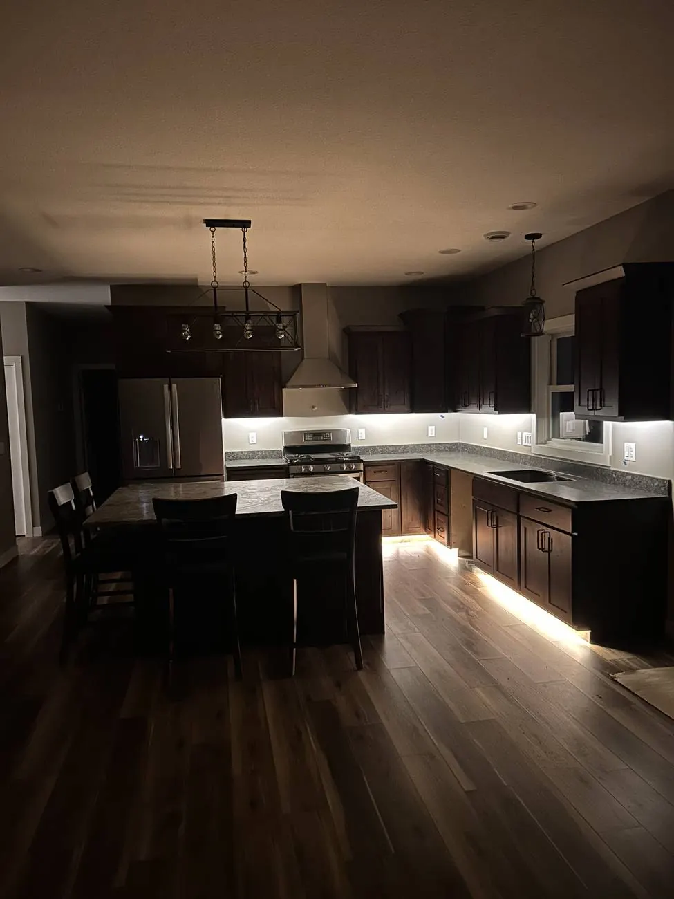 Dark kitchen lit only by under-cabinet and toe-kick LED strips